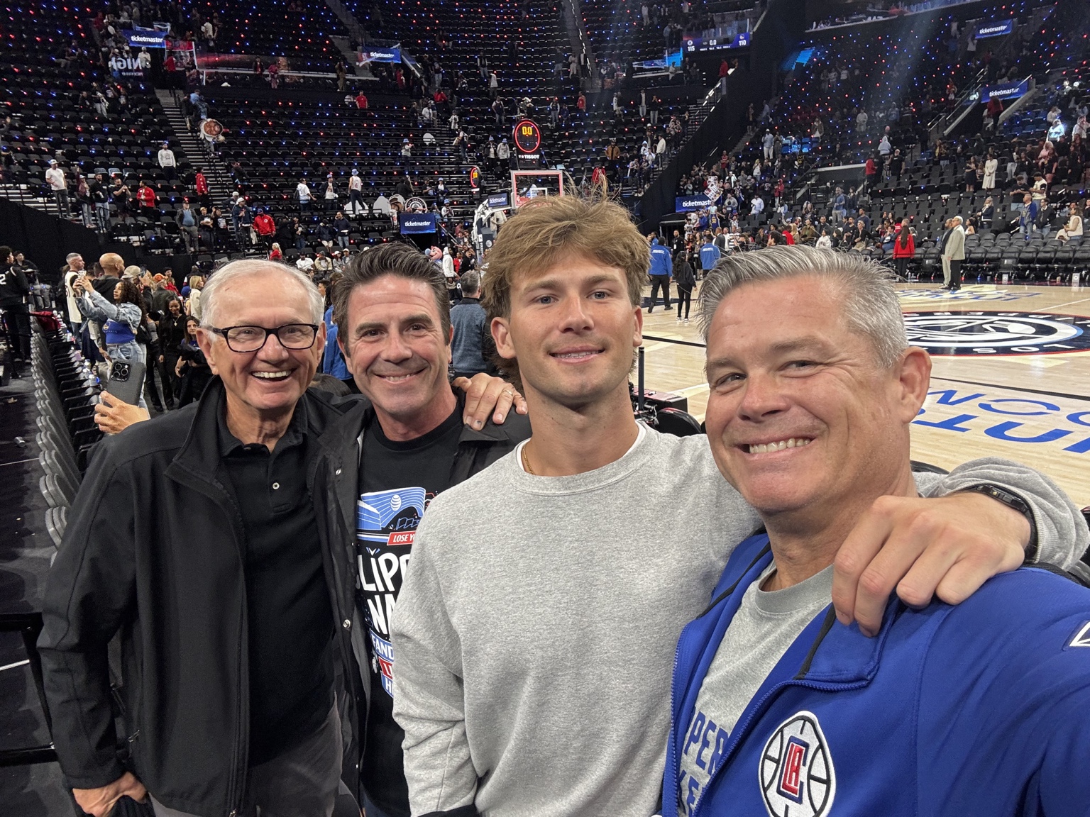 Four fans smiling together courtside after a basketball game