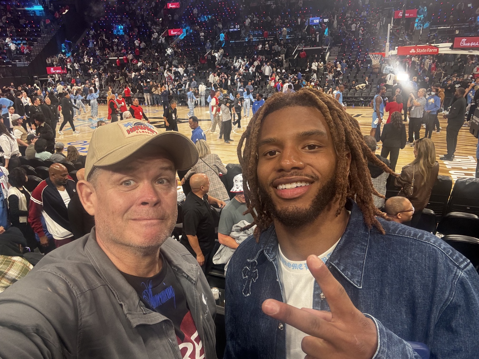 Two people taking a selfie with the basketball court behind them