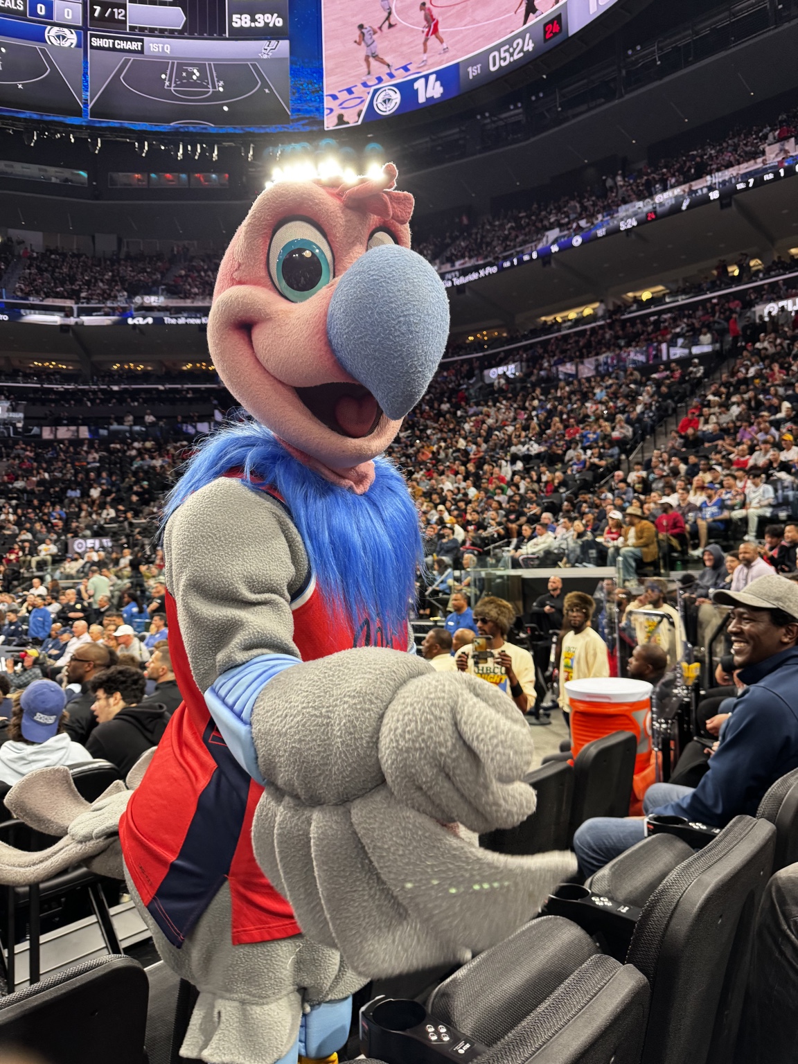 The team mascot reaching toward the camera among the arena seats